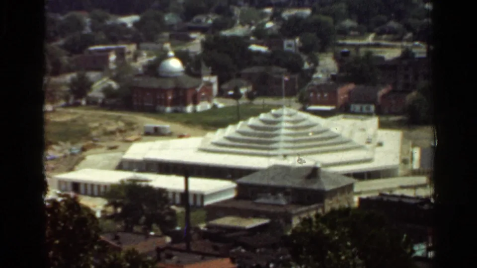 1965 Arkansas 8mm frame with the tiered pyramid-like roof building in the foreground and a domed brick building beyond.