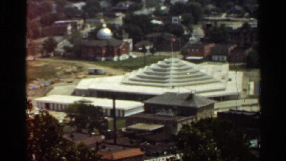 1965 Arkansas 8mm frame showing the tiered roof building and domed brick structure from a slightly shifted elevated viewpoint.