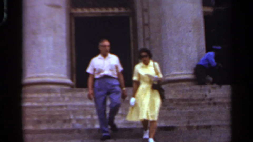 The pair continues down the stone steps of a grand Arkansas building, with the woman carrying a dark purse and wearing sunglasses.
