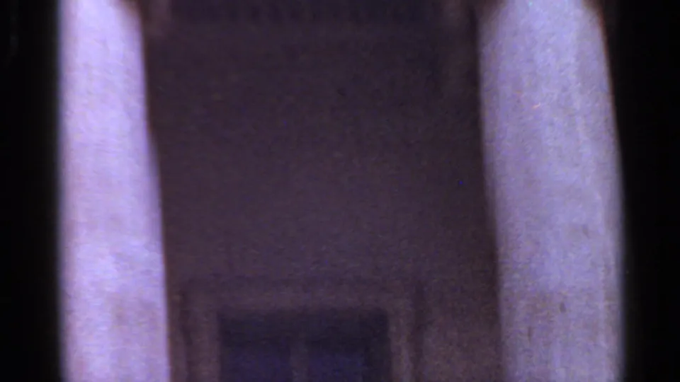 Handheld 1965 8mm view of tall stone columns and a shadowed architectural opening at the building exterior.