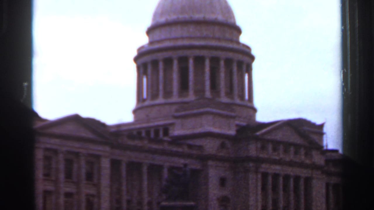 Closer view of the capitol dome and front facade under a bright cloudy sky.