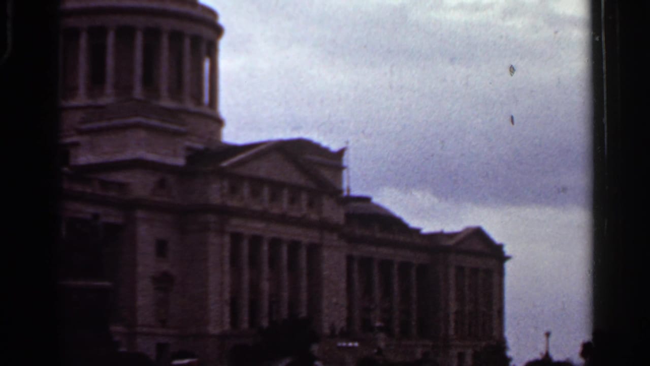 Columned domed building seen in soft 8mm footage under a cloudy sky.