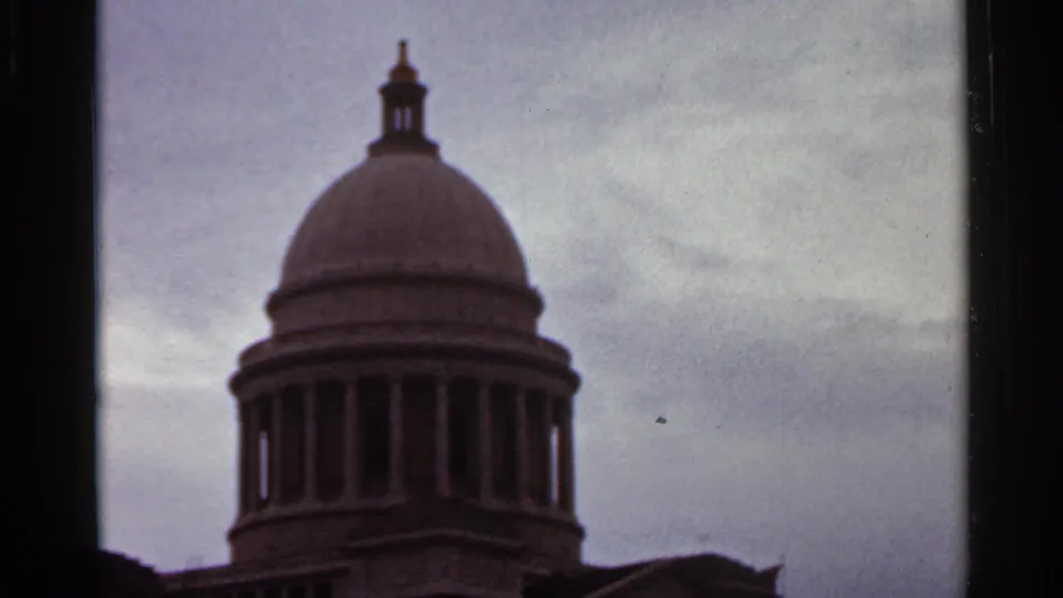 1965 Arkansas 8mm frame centered on a large civic-style dome and surrounding columns, with muted color and film-edge borders.