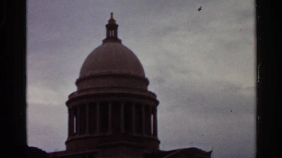 1965 Arkansas 8mm frame showing the domed upper section of a classical building, darkened by exposure and framed by film borders.