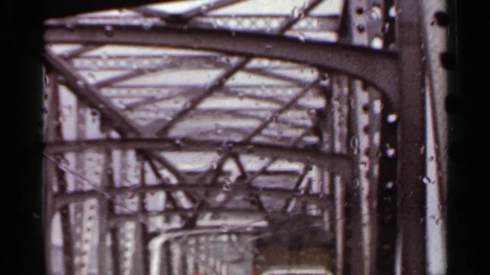 Riveted metal bridge beams and overhead crossbracing seen from a moving car in Arkansas, 1965.