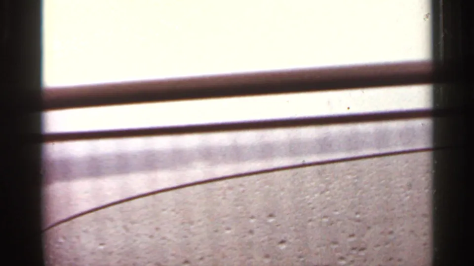 Passenger-window view of bridge railings against a bright sky during a 1965 Arkansas bridge crossing.