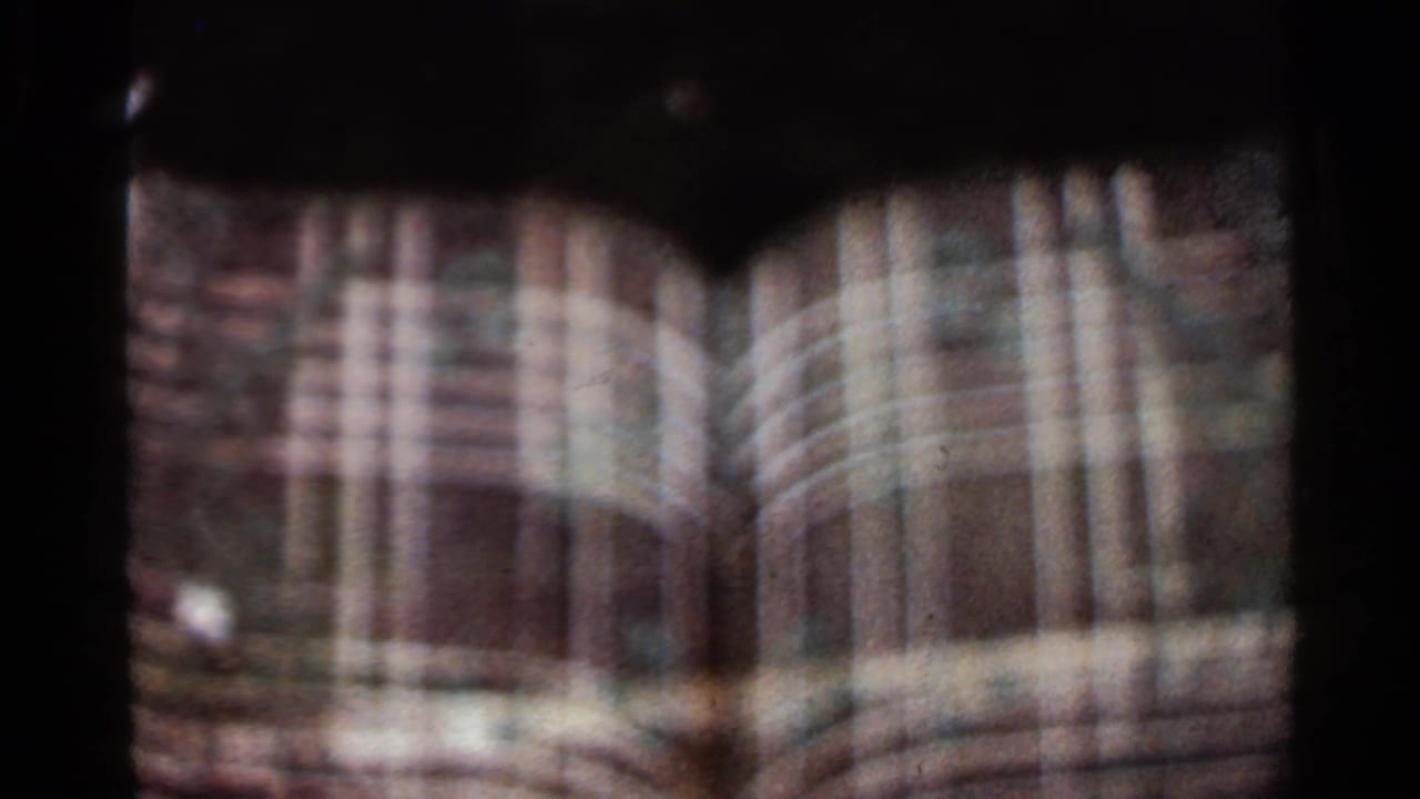 Soft, overlapping 8mm frame of a tan building facade and dark fountain form.