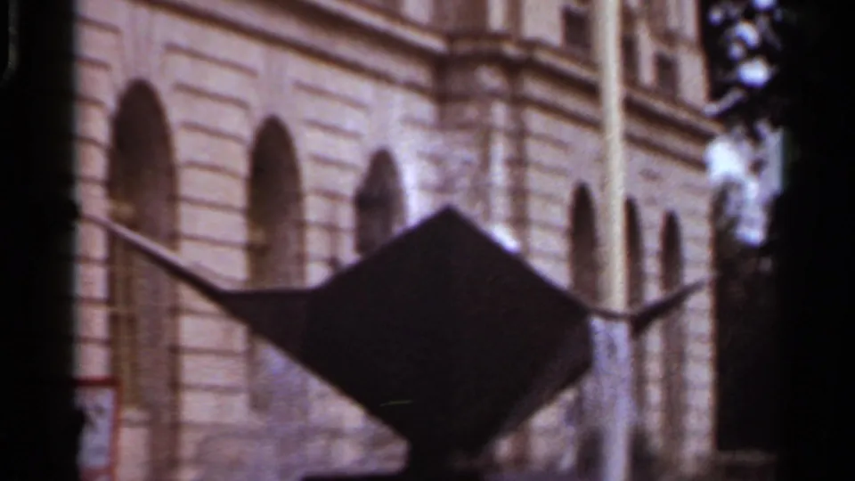 1965 Arkansas train-view frame with a silhouetted angular sign or sculpture against a large stone building.