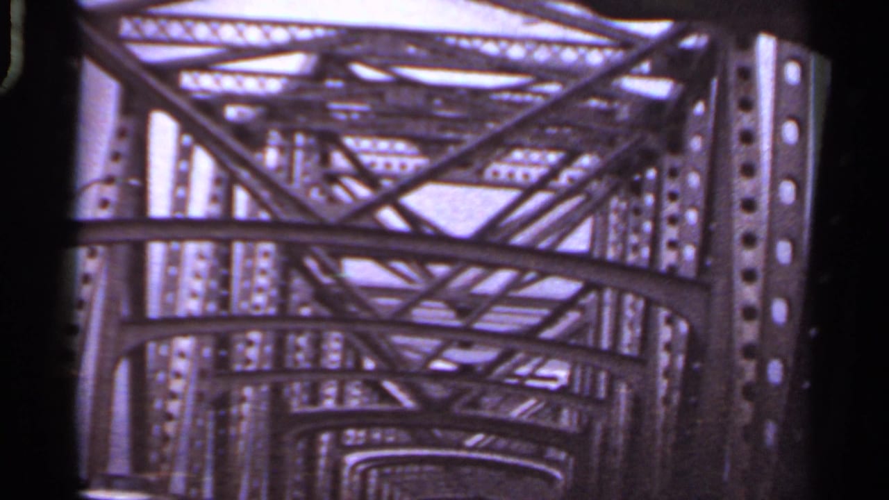 1965 Arkansas 8mm view looking forward through a steel truss bridge from a moving car.