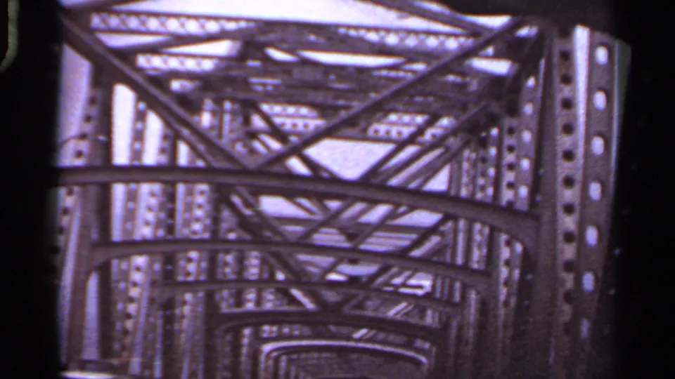 1965 Arkansas 8mm view looking forward through a steel truss bridge from a moving car.