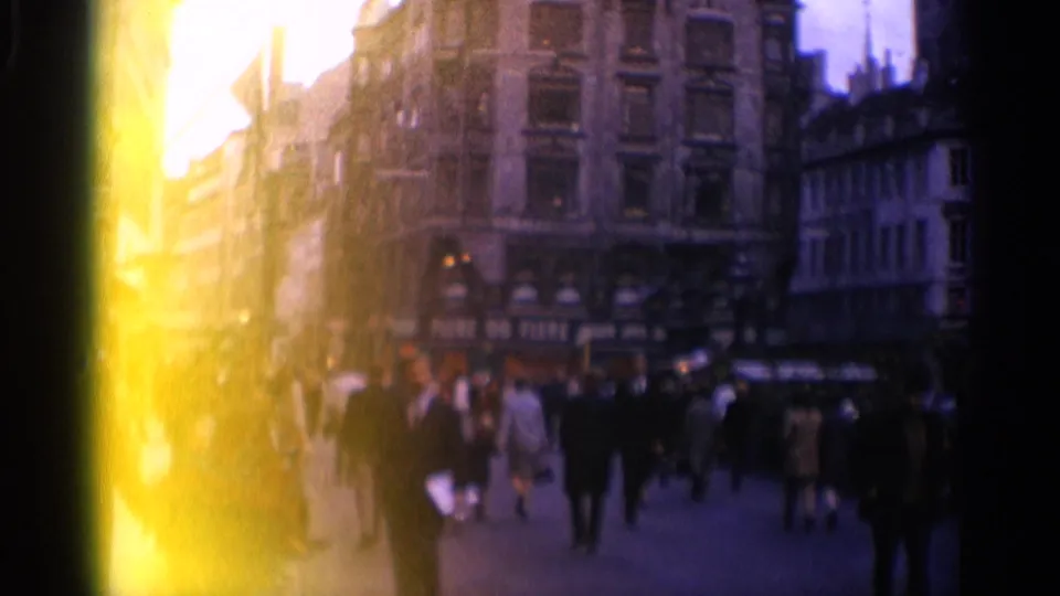 1965 Copenhagen street scene with pedestrians, shopfront awnings, tall buildings, and a bright yellow film flare along the left edge.