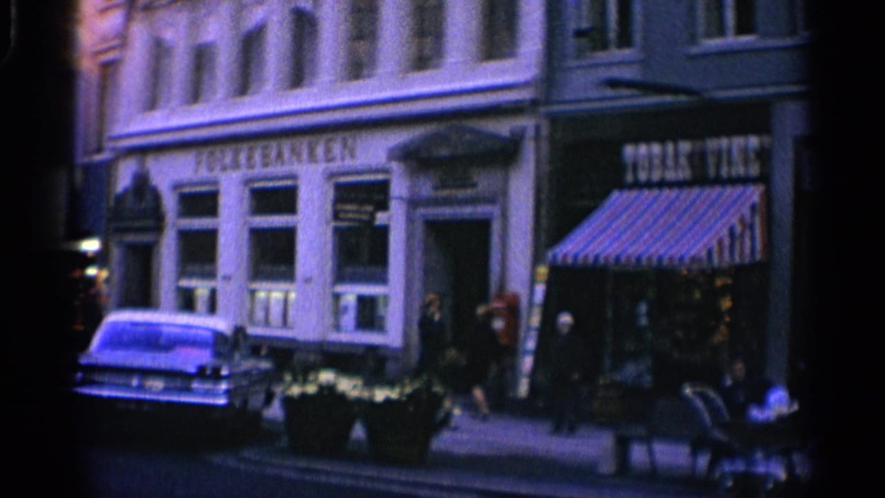 Street facade with Folke Banken, Tobac Vine storefront, pedestrians, and parked car.