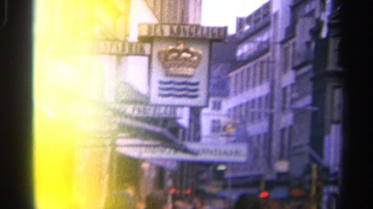 Overexposed street view with crown-and-waves sign, awnings, buildings, and traffic blur.