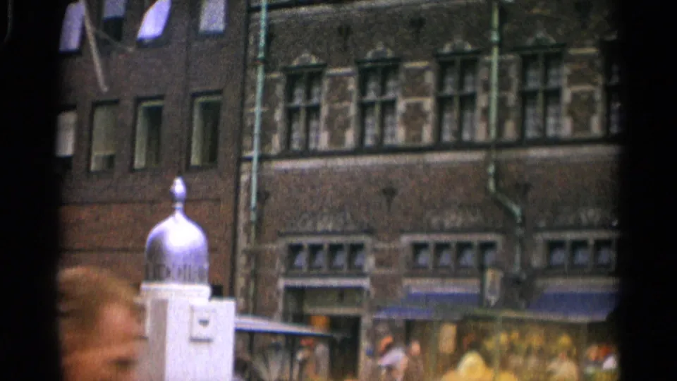 Copenhagen street scene with ornate brickwork, storefront awnings, pedestrians, and a silver-domed fixture in the foreground.