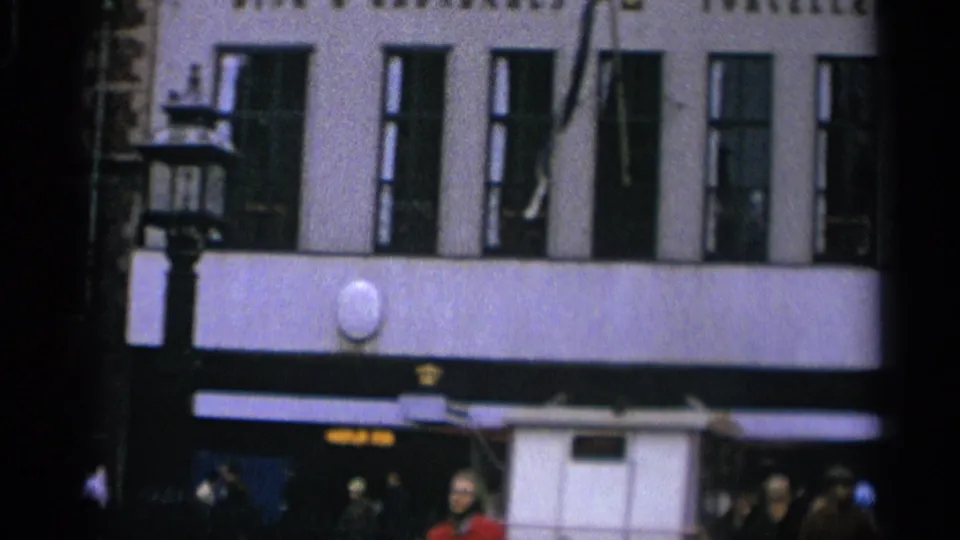 Copenhagen street exterior showing tall windows, dark awnings, pedestrians, and partial signage along the lower storefront level.
