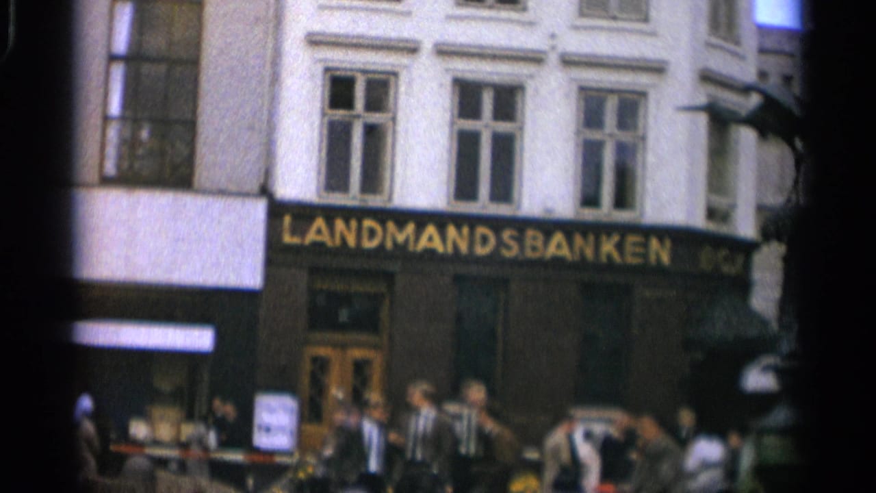 Bank frontage with pedestrians and part of a bronze statue at right.