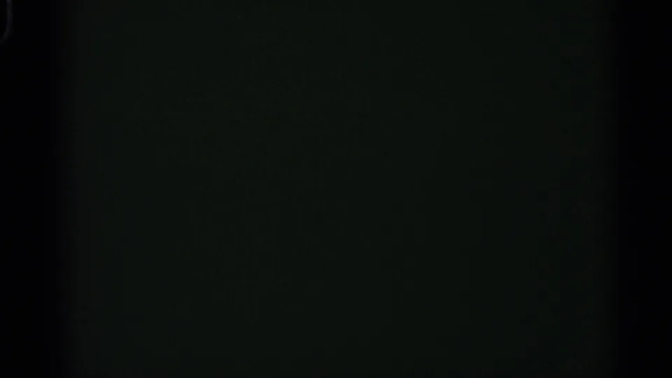 A dark, green-tinted 8mm frame with grain and minimal visible street detail.