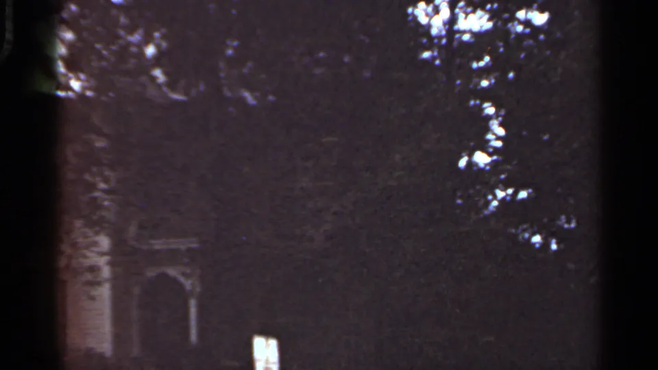 Kansas City home-movie frame from 1965 with a shadowed house entrance seen through dense trees.