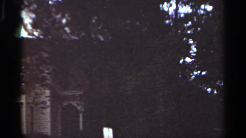 1965 Kansas City 8mm still showing a partly obscured residential exterior with pale trim and an arched entry.