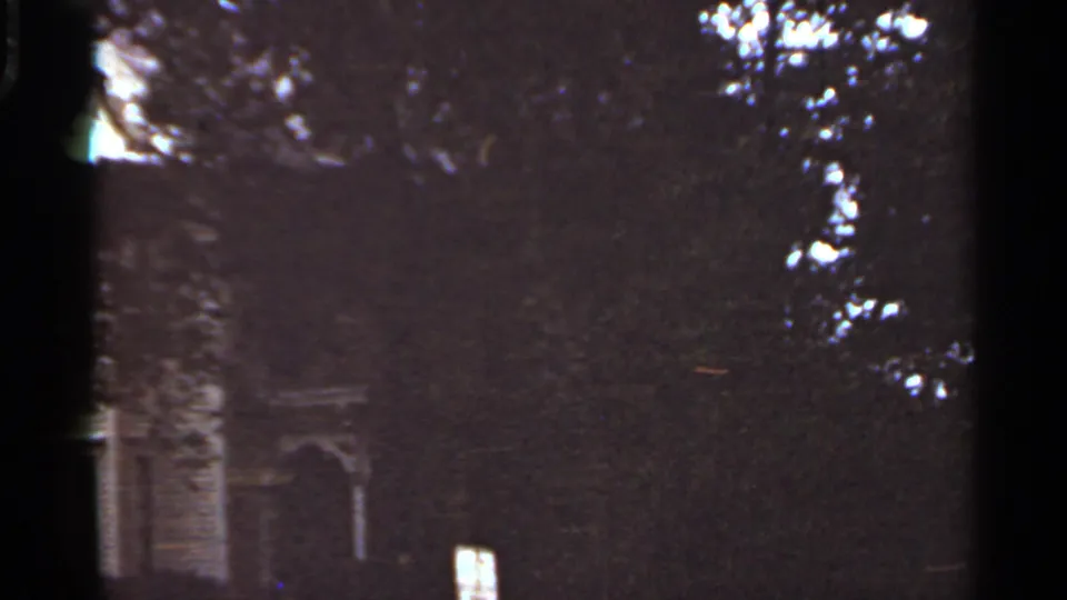Final 1965 Kansas City frame where dense foliage nearly hides the residential facade and arched doorway.