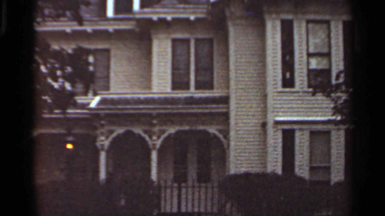 Closer view of the same house facade with arched porch and dark windows.