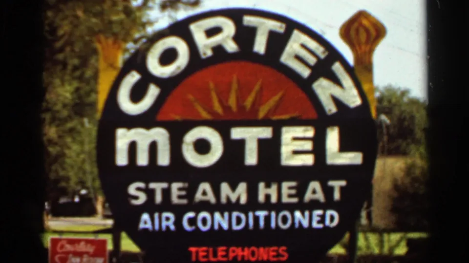 Close 1965 view of the Cortez Motel roadside sign, showing amenity text and a small sign near the base.