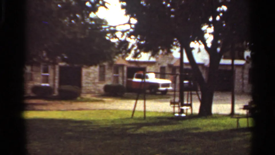 1965 Kansas City suburban exterior showing a swing set, large shade tree, lawn, and red-and-white pickup near the house.