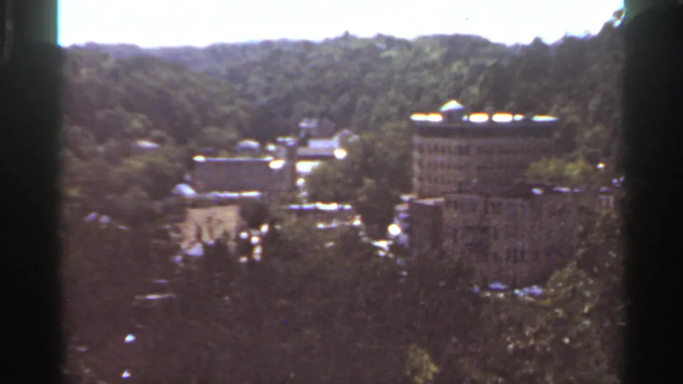 A wider 1965 Kansas City view shows several buildings across a wooded slope with visible 8mm frame borders.