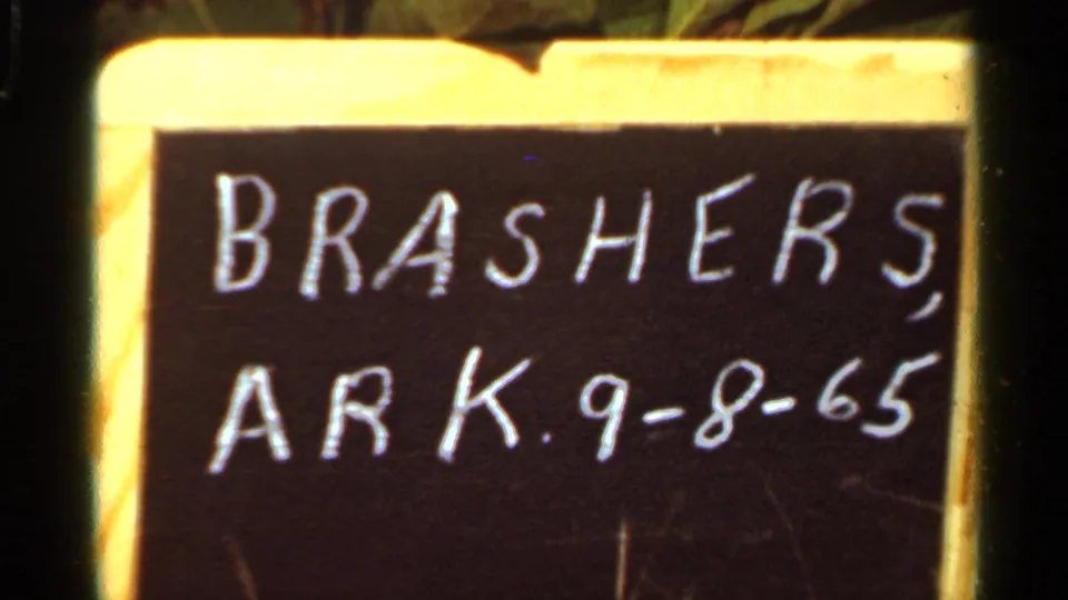 Close 8mm frame of a handwritten board reading BRASHERS, ARK. 9-8-65, likely serving as a location and date marker.