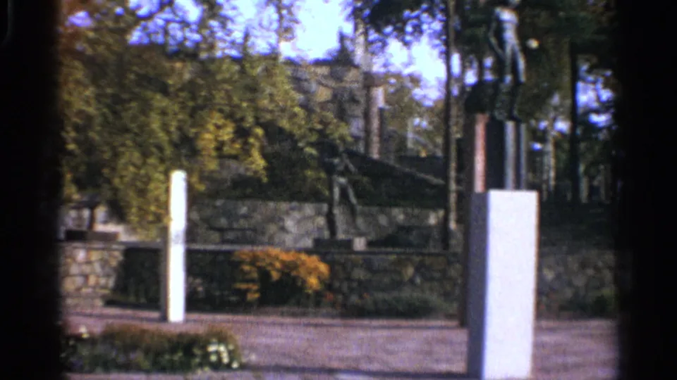 1965 Leningrad park scene with white pillars, stone landscaping, trees, shrubs, and a partially seen modernist sculpture.