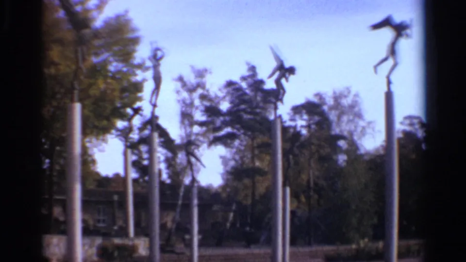 1965 Leningrad park scene with multiple modernist sculptures on tall columns, trees, open sky, landscaping, and a distant building.