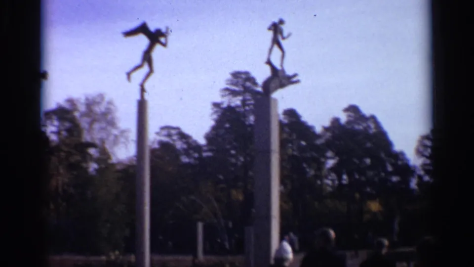 1965 Leningrad park view with two elevated modernist figures and distant visitors near the base of the columns.