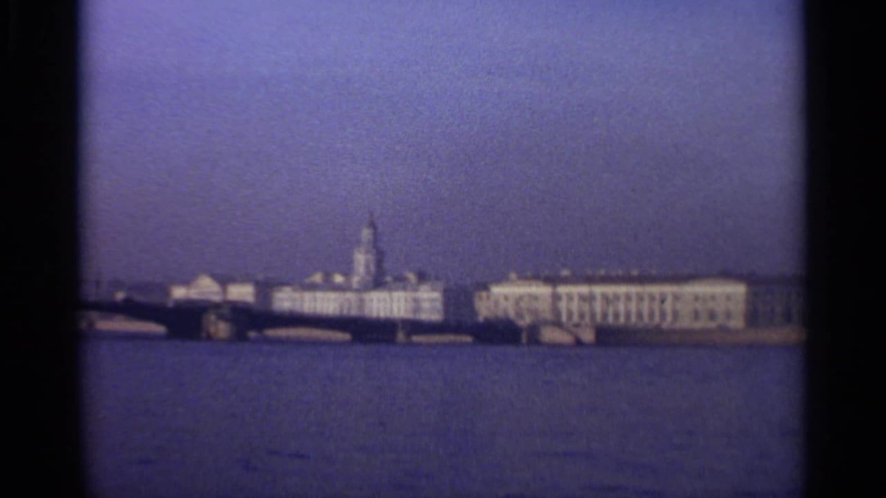 Distant waterfront buildings and a spire across wide water.