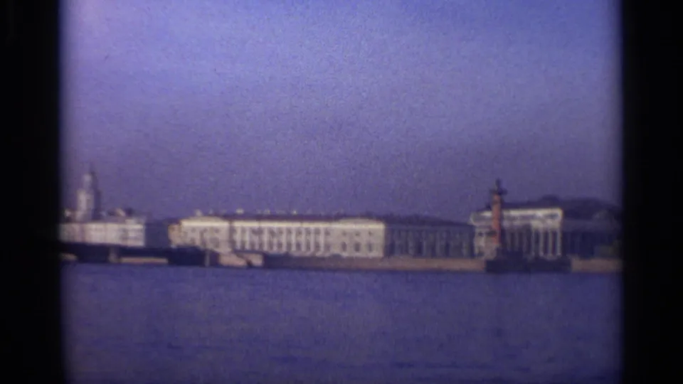 Leningrad waterfront pan showing classical buildings and a red-and-white shoreline tower or marker across the water.
