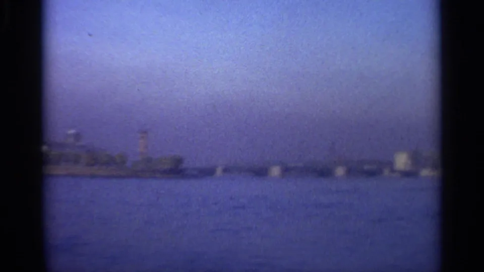 A soft 8mm view of Leningrad's waterfront, showing a tower and low shoreline forms across blue water.
