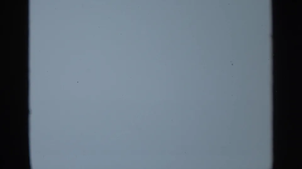 Blue-tinted blank 8mm frame from the 1965 Leningrad clip, showing grain and dark film-edge bands.