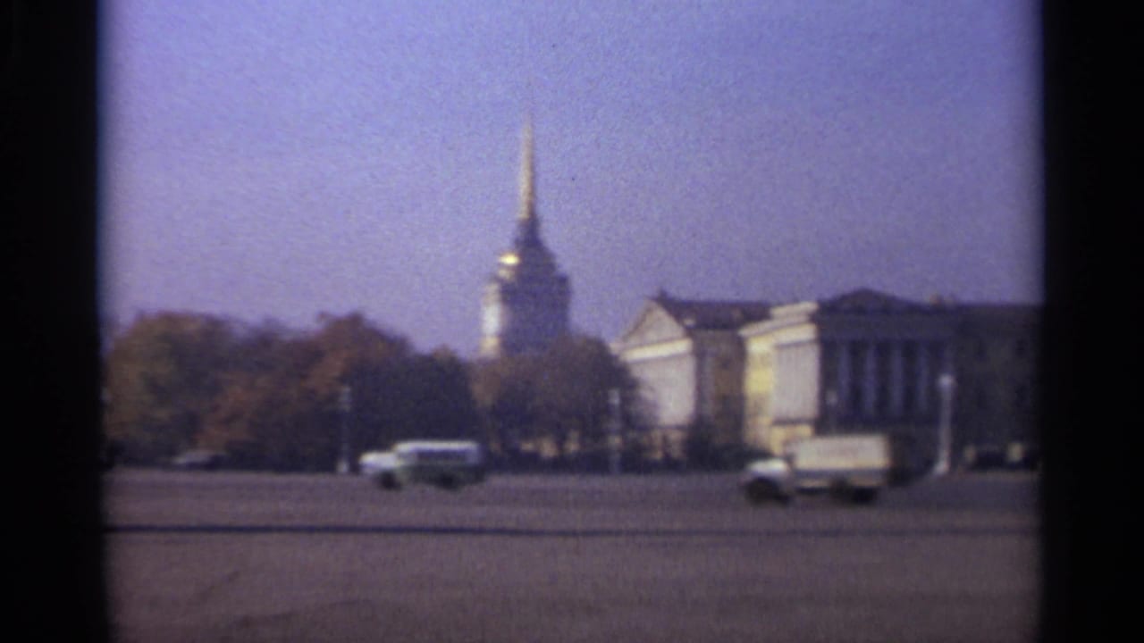 1965 Leningrad street view with cars and a truck moving across a large square near classical facades and a gilded spire.