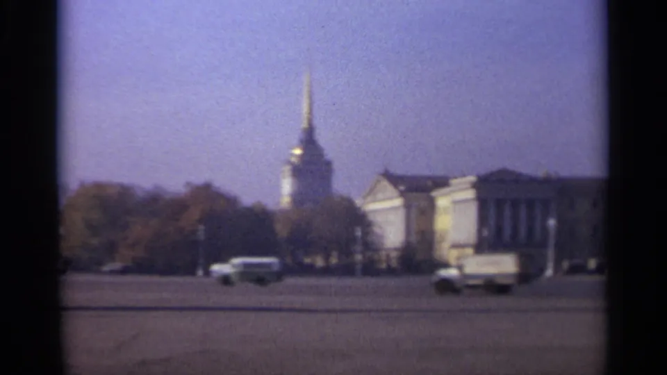 1965 Leningrad street view with cars and a truck moving across a large square near classical facades and a gilded spire.