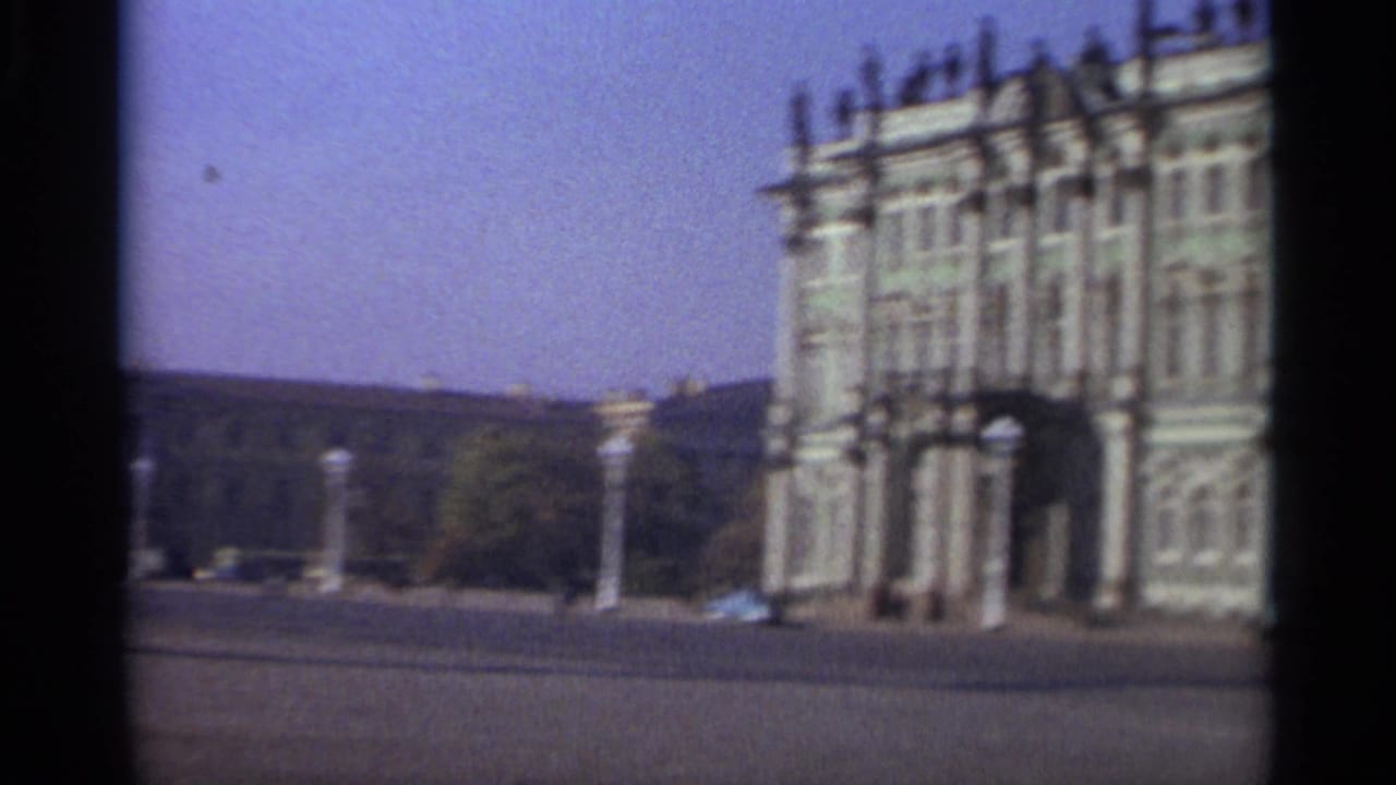 1965 Leningrad 8mm frame showing a grand green-and-white facade across a wide open square.