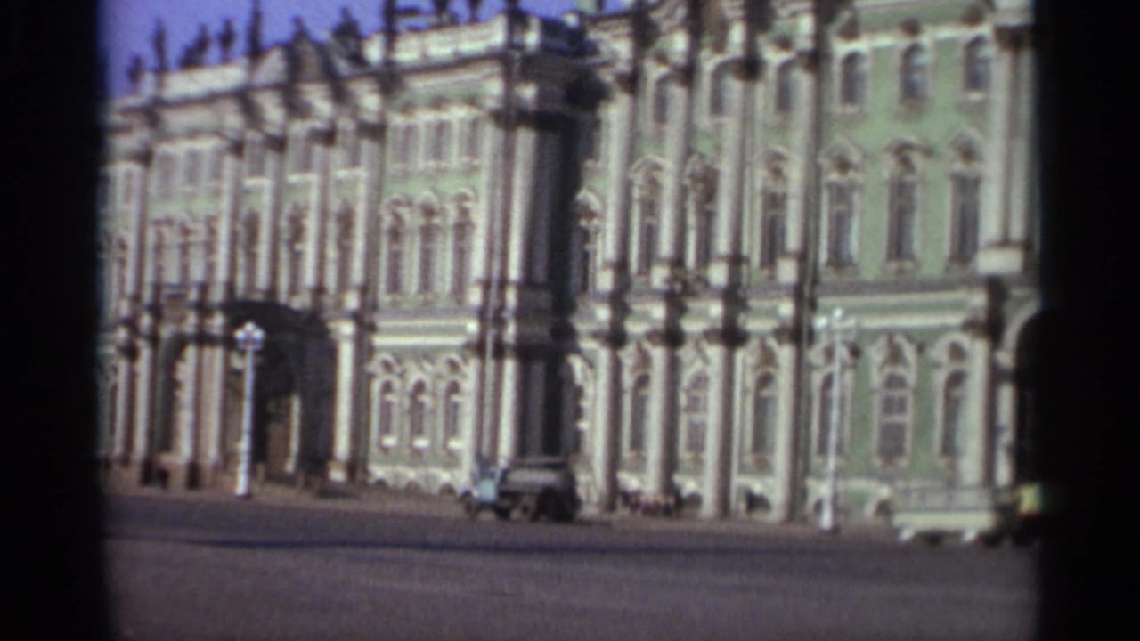 1965 Leningrad frame with the ornate building facade, arched windows, and a vehicle near the curb.