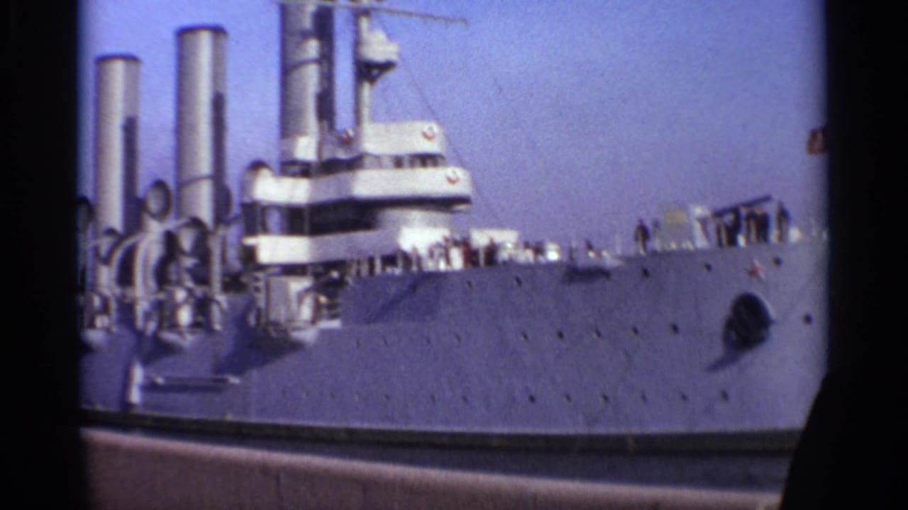 Large gray military ship docked under a clear sky.