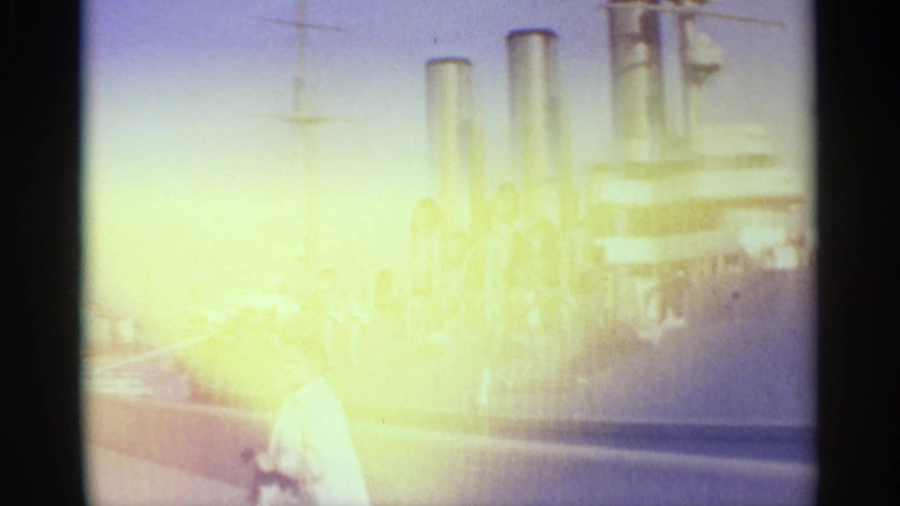 Overexposed 1965 Leningrad dockside view with the military ship in the background and a person near the foreground.