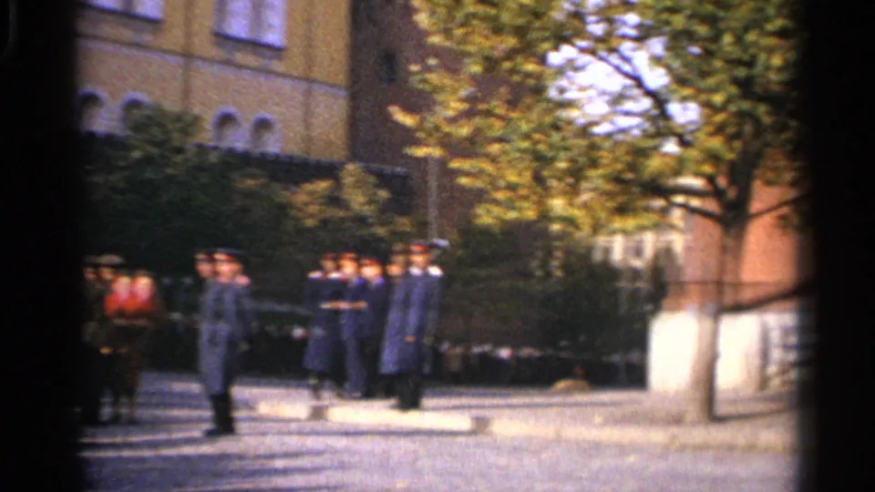 1965 Leningrad 8mm frame with several uniformed men gathered outside beside a tree and masonry building.