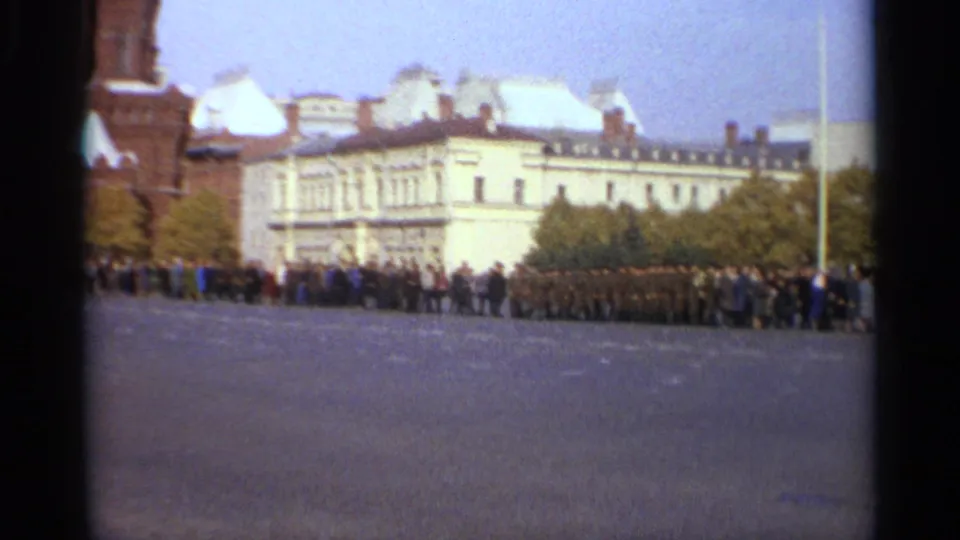1965 Leningrad view across a large square toward pale historic buildings, with a long public line and uniformed figures standing nearby.