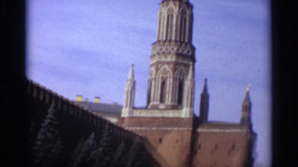 1965 8mm frame looking up at a red-brick wall and ornate tower, filmed from a visitor-like angle.