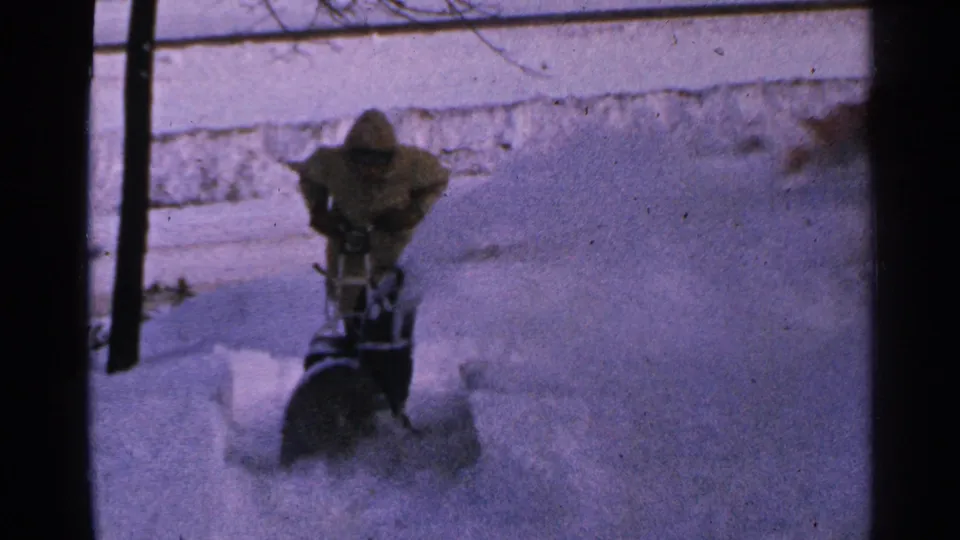The 8mm frame shows the operator leaning into the snow blower while clearing a path through deep Minnesota snow.