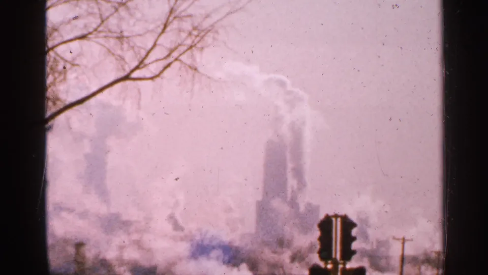 The final frame shifts to a hazy winter view of distant smokestacks, bare branches, and utility lines in Minnesota.