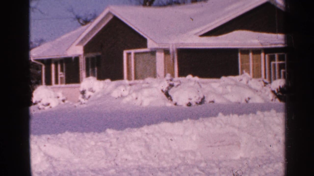 Snow-covered single-story house behind deep winter drifts.