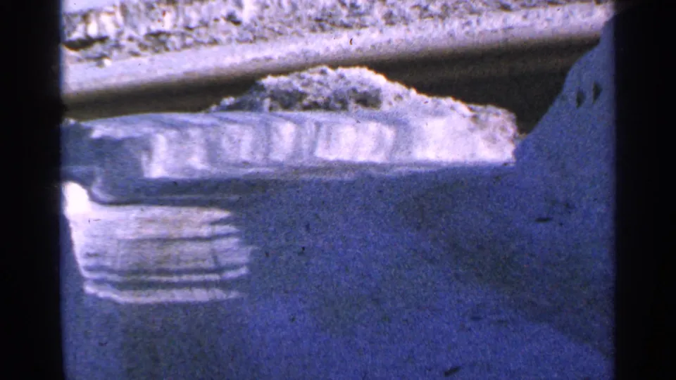 Final 8mm frame shows a blue-toned snowy surface and ledge near the feeding area, with no birds clearly visible.