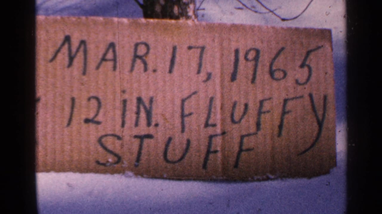 Handwritten cardboard sign reads Mar. 17, 1965 and 12 in. fluffy stuff in snow.